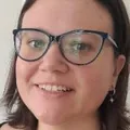 Emma Johnston, smiling, with round dark glasses and a necklace