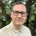 James Taylor, with short dark hair and rectangular black glasses