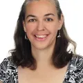Sandy Millin, smiling, with shoulder-length dark hair and a black and white top