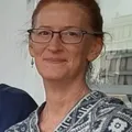 Stephanie Wilbur, with dark rectangular glasses and earrings